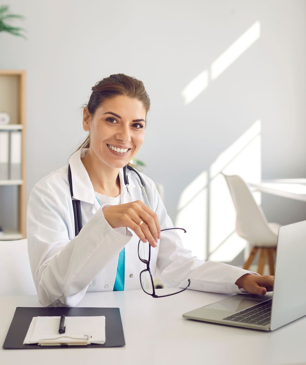 A primary care physician smiling at her desk in a clinic office